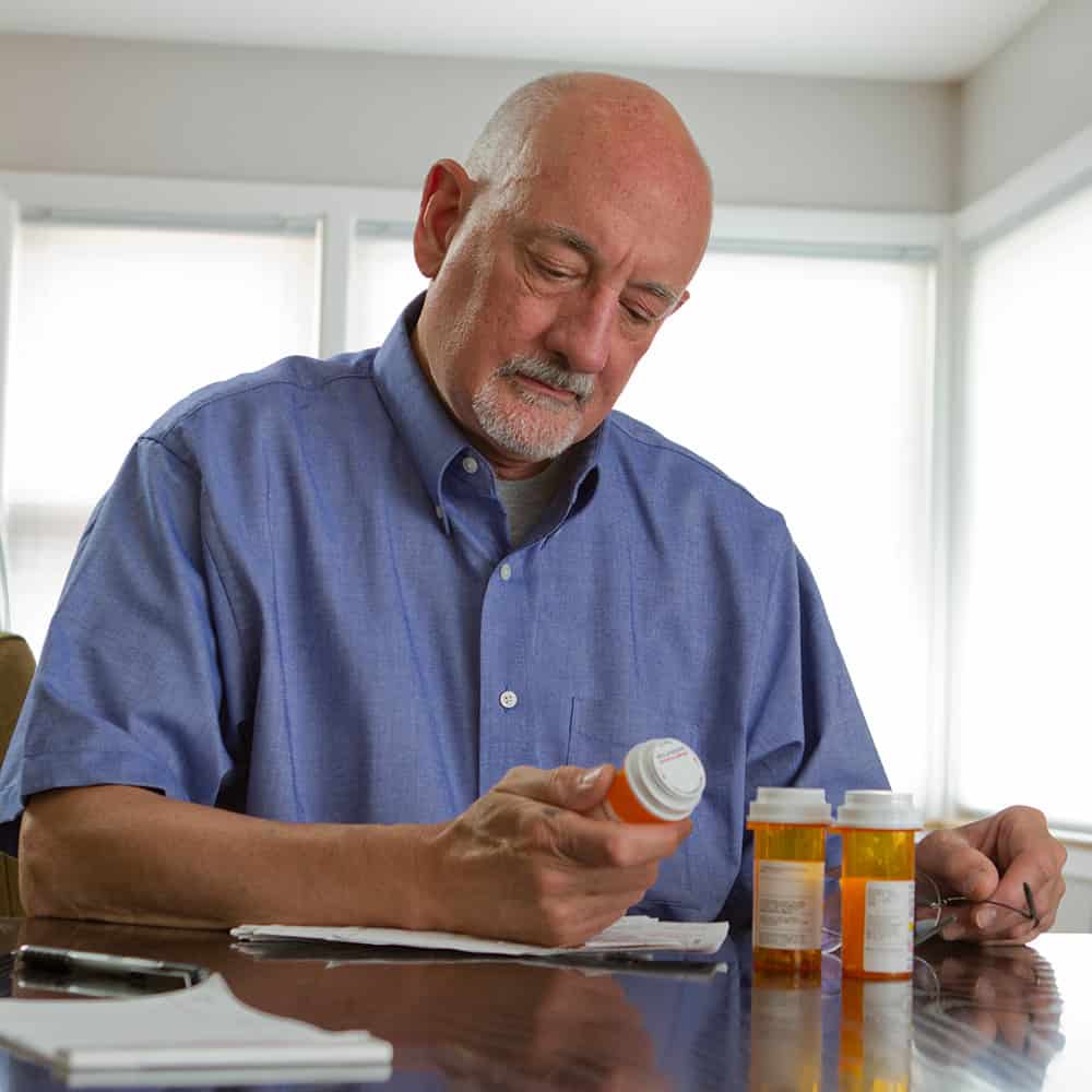 older man looking at pill bottle