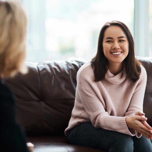 Therapy, happy women have a conversation on sofa and speaking or talking with a psychologist. Mental health or communication, support or consulting and people on couch have a discussion together.