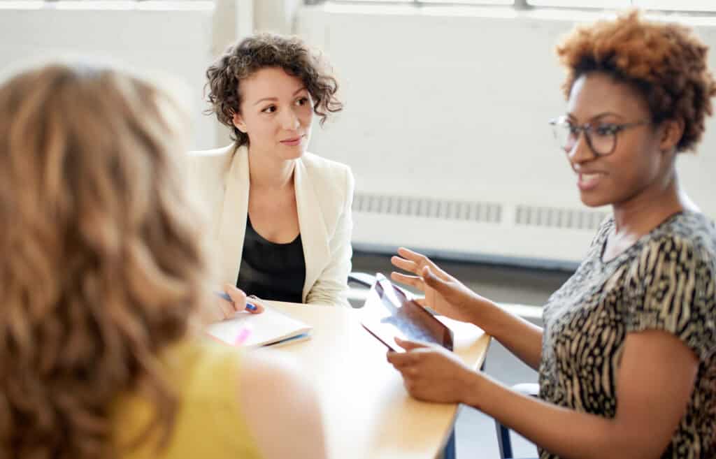 Candid picture of a female boss and business team collaborating. Filtered serie with light flares, bokeh, warm sunny tones.