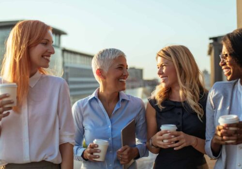 Portrait of four business women discussing about the next project with coffee on the rooftop.