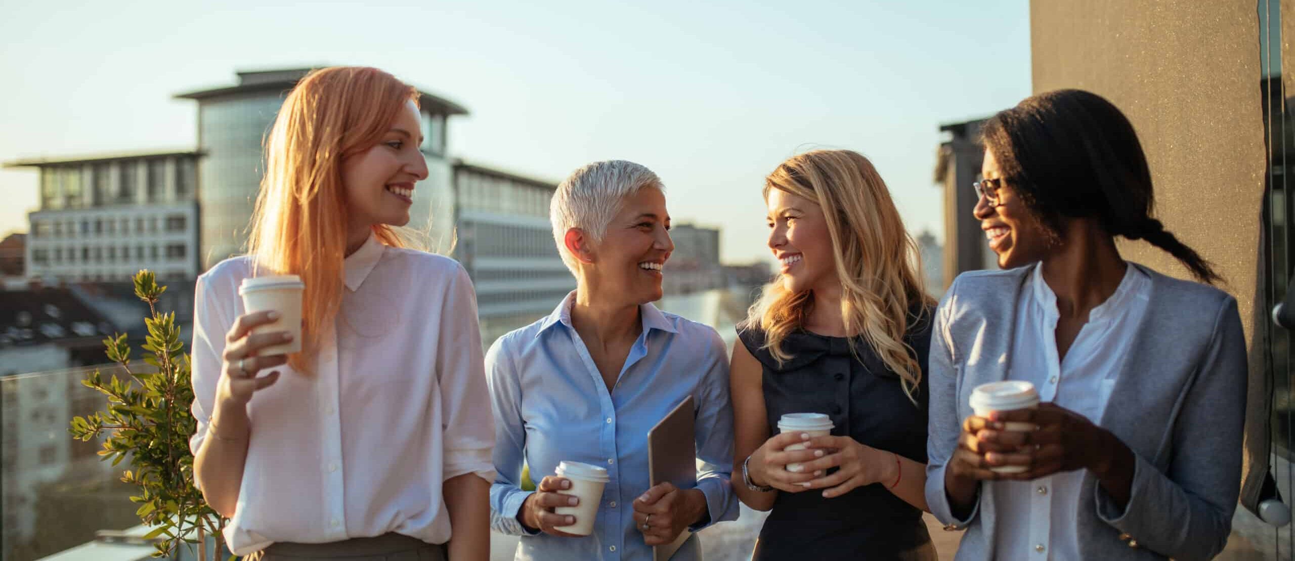 Portrait of four business women discussing about the next project with coffee on the rooftop.