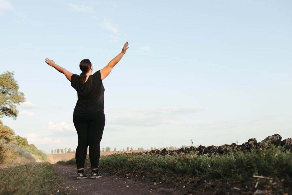 Overweight woman celebrating rising hands to sky